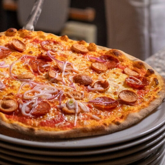 Bannière du cinquième article sur comment cuire sa pizza maison au four, avec une belle pizza cuite au four sur une assiette