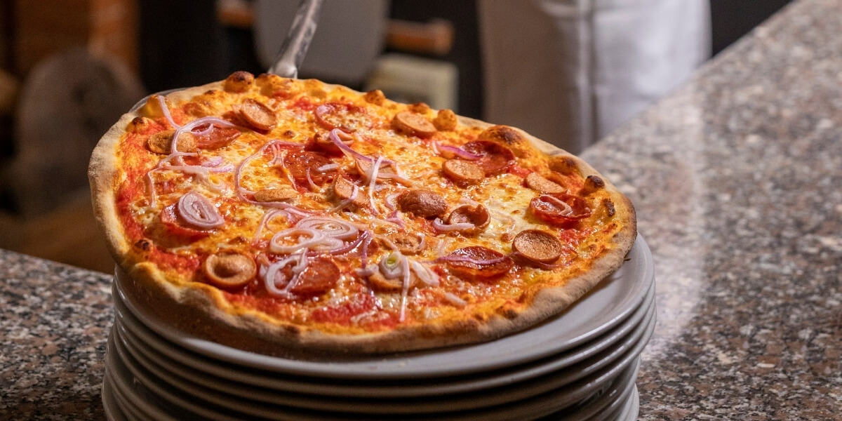 Bannière du cinquième article sur comment cuire sa pizza maison au four, avec une belle pizza cuite au four sur une assiette