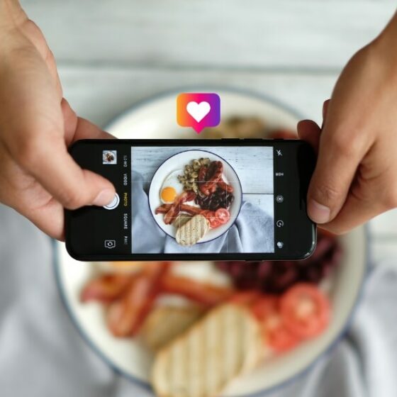 Bannière du septième article sur les meilleurs comptes Instagram de cuisine à suivre, avec un smartphone qui prend en photo un plat.