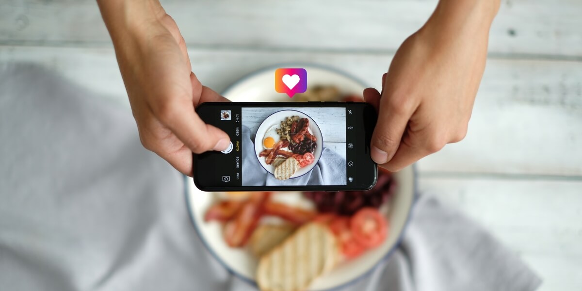 Bannière du septième article sur les meilleurs comptes Instagram de cuisine à suivre, avec un smartphone qui prend en photo un plat.