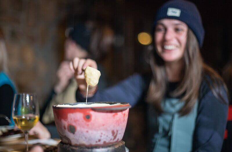 une femme mange une fondue au fromage en tenue de ski