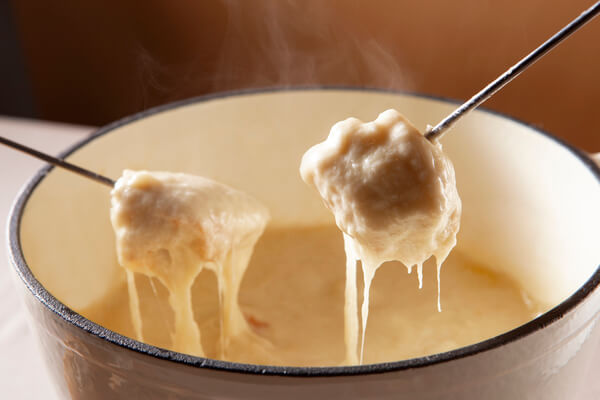 Morceaux de pain trempés dans un caquelon à fondue au fromage. 